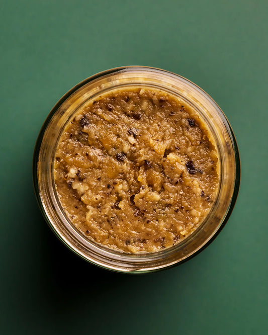 Jar of brown paste on a green background
