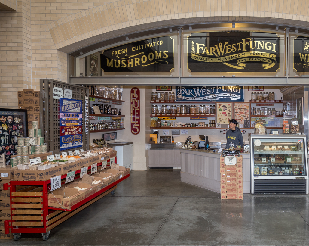 Grocery store interior with 'Far West Fungi' mushroom section and staff behind the counter.