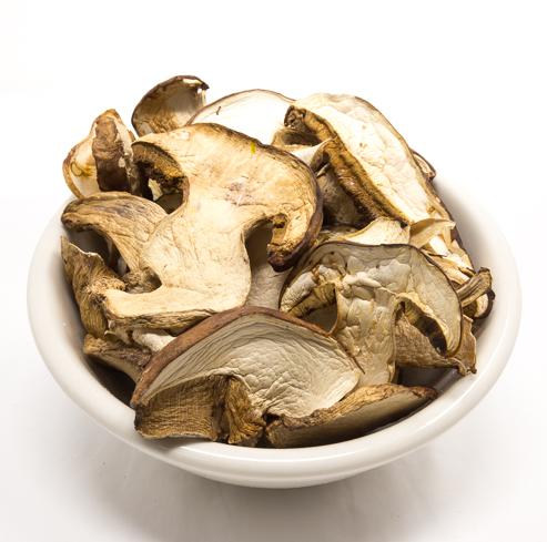 Dried mushrooms in a white bowl on a white background