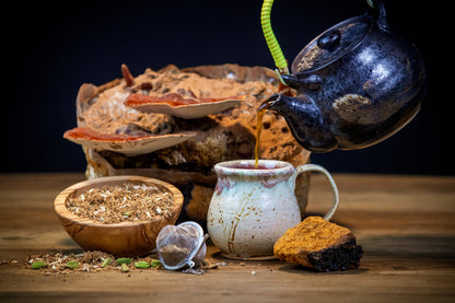 Tea being poured from a teapot into a cup on a wooden surface with tea leaves and a teacup in the background.